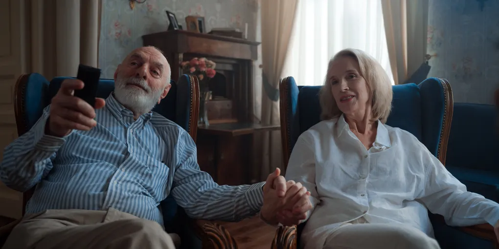 Couple âgé assis dans des fauteuils anciens, se tenant la main