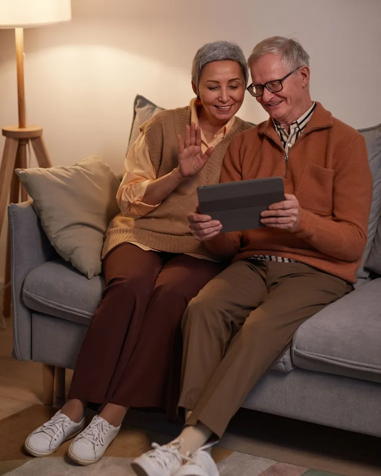 Couple de grands-parents regardant des photos de famille sur une tablette, lumière chaleureuse