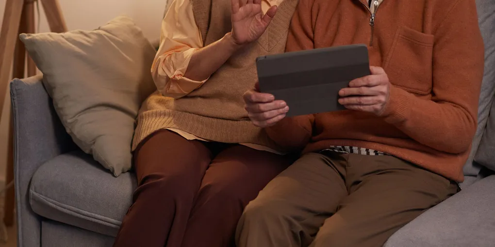 Un couple de seniors assis dans leur salon regarde des photos sur une tablette